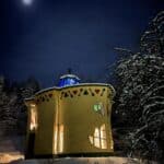 Värikäs keltainen, lehden muotoinen talo jossa on lehden muotoiset ikkunat yöllä.