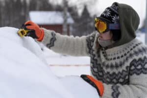 Nainen villapaidassa veistämässä jäätä.